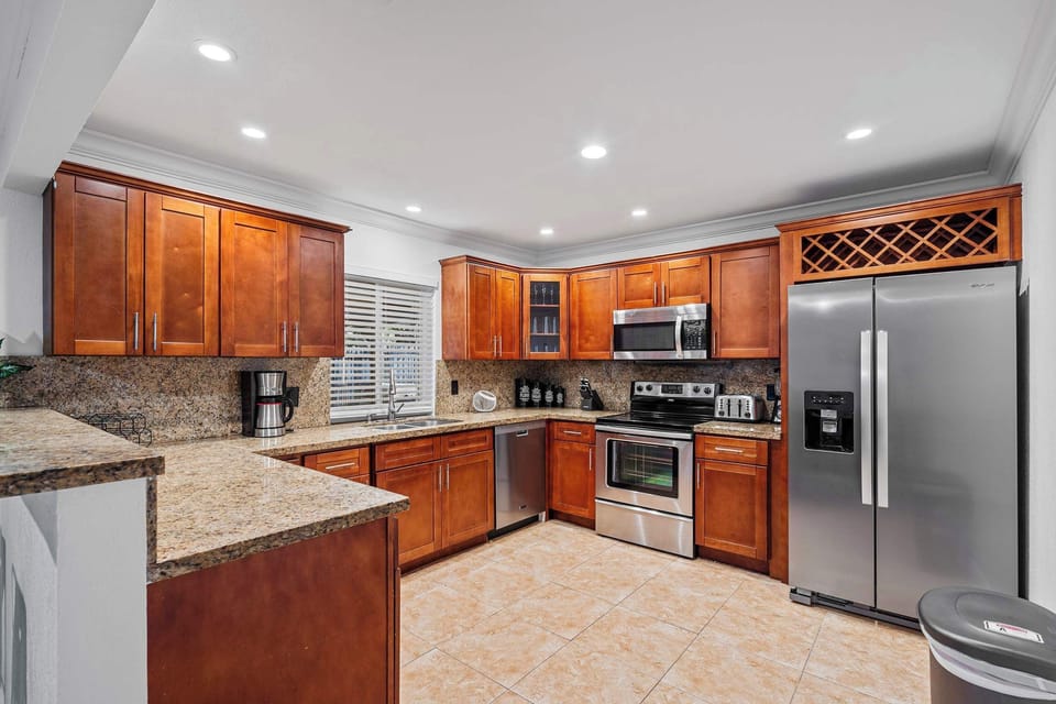 Kitchen with wood cabinets, electric range and large fridge.