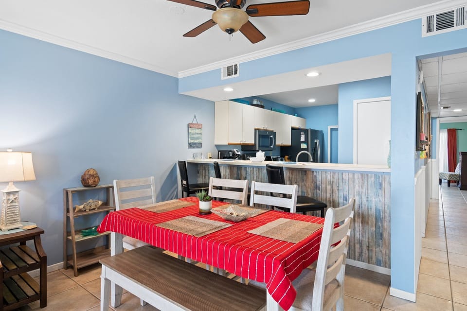 Dining area with a red-striped tablecloth and open kitchen in a cozy setting