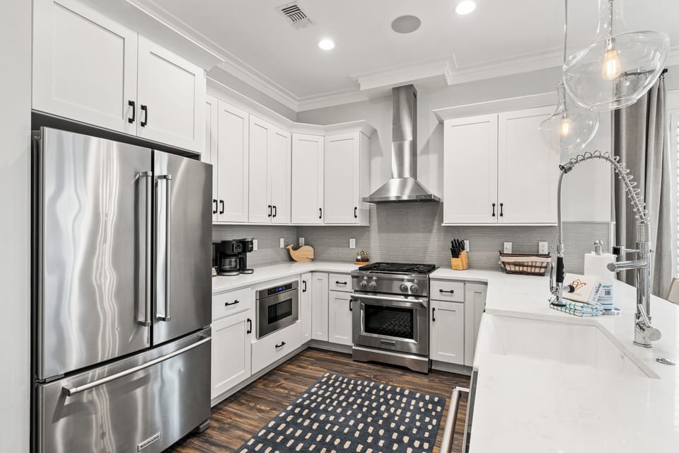 Your fully equipped modern kitchen awaits with stainless steel appliances, pristine white cabinets, and everything you need to create memorable meals.