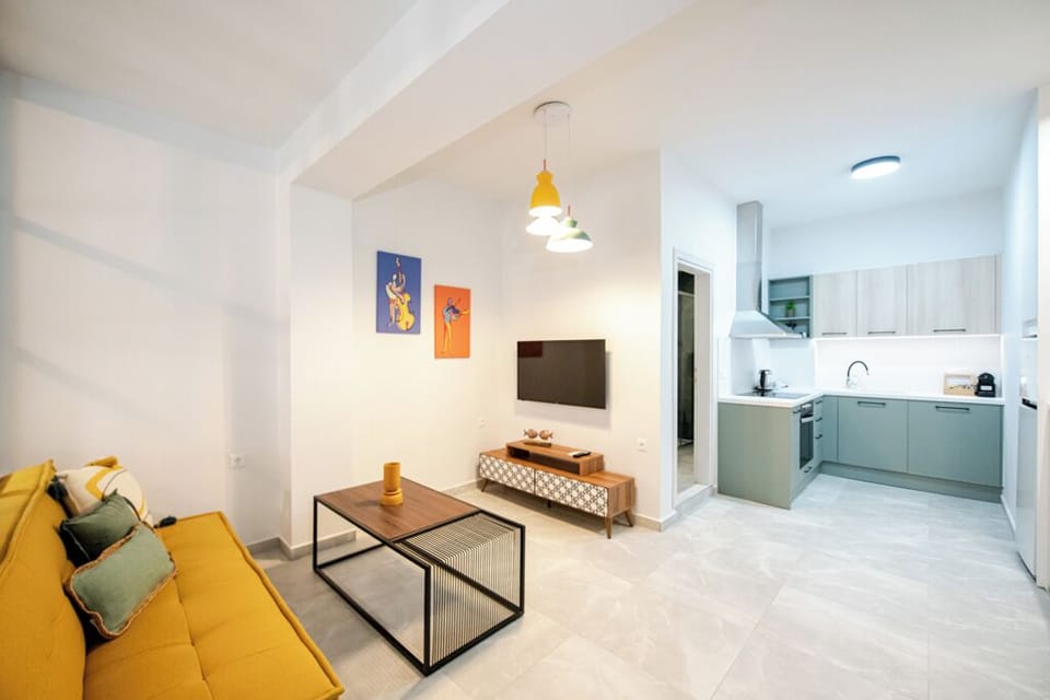 A cozy, practical space with seating, modern TV, full kitchen, and vibrant art.