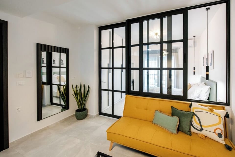 A chic living space with a mustard sofa and glass partitions.