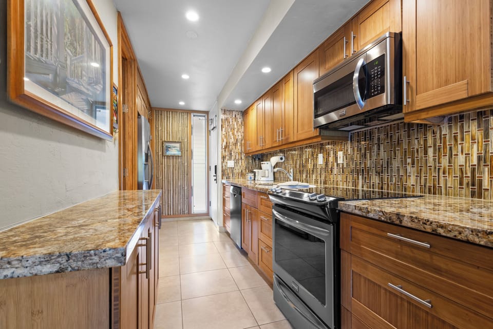 Step into a sleek galley kitchen where granite counters meet a stunning mosaic backsplash. You'll find every convenience—stainless steel appliances, ample cabinetry, and room to create memorable meals together.