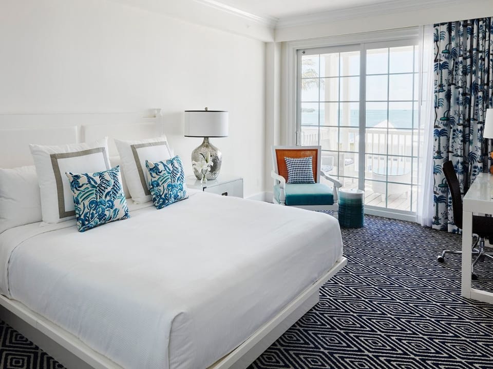 Spacious and bright bedroom with soft hues and expansive windows overlooking tranquil surroundings.
