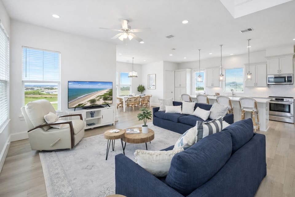Bright open-concept living room with modern coastal decor, large windows, and natural light—perfect for luxury beach house gatherings.