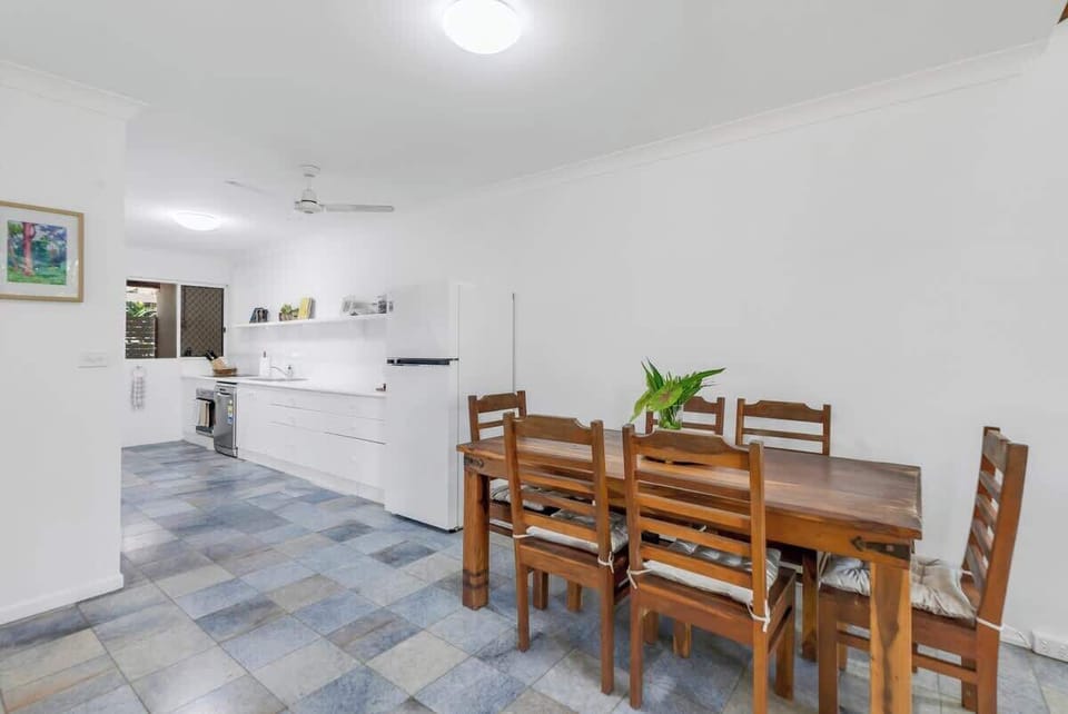 Share meals and memories around the wooden dining table, where cushioned seating for six and a ceiling fan create the perfect setting for relaxed gatherings.