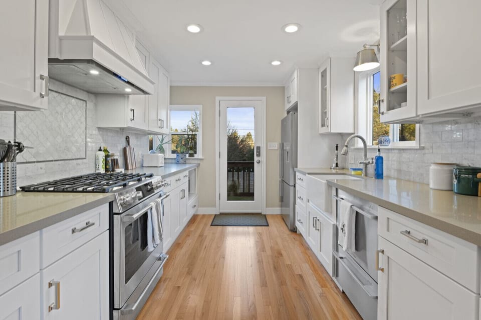 KITCHEN: A fully equipped, stylish space featuring white shaker cabinets, quartz countertops, and a marble-finish backsplash—both elegant and functional.