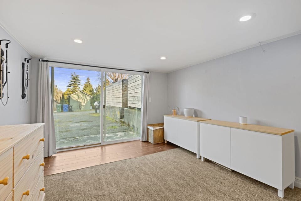 FAMILY ROOM: Spacious recreation area with a white sectional sofa, electric fireplace, and wall-mounted TV—perfect for entertainment, exercise, or relaxation.