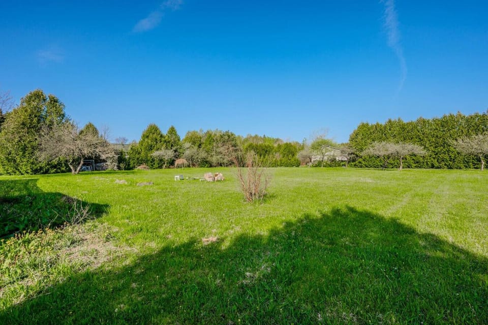 The large yard offers endless possibilities for recreation and relaxation, framed by mature trees that add to the property`s charm.