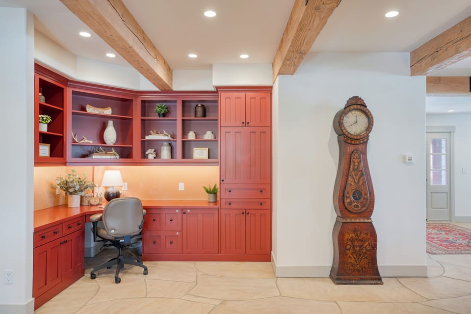 Beautiful large desk on main level, perfect for remote work or study.  This cabinet is full of games and coloring books.  Also shown is the ornate grandfather clock shipped from Sweden many years ago.