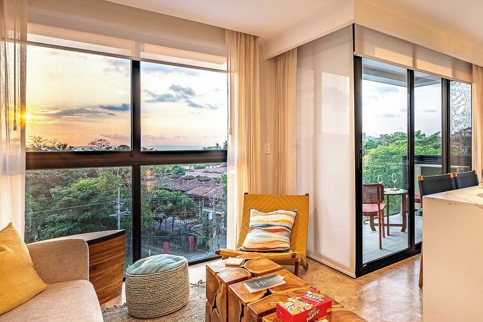 Living area with floor to ceiling windows with panoramic ocean and sunset view