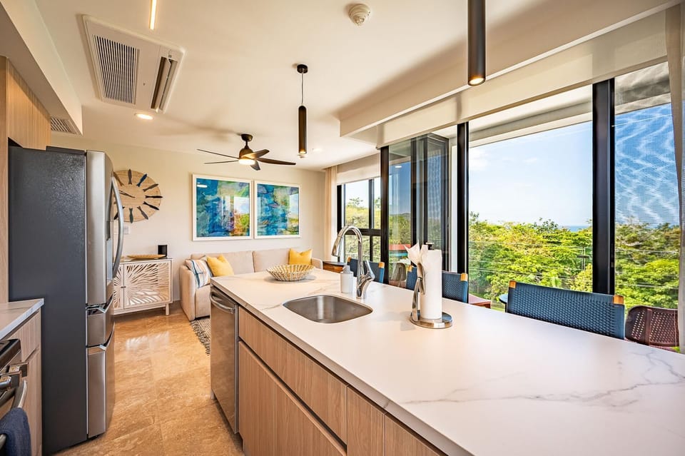 Large kitchen area with breakfast counter with panoramic ocean and sunset view