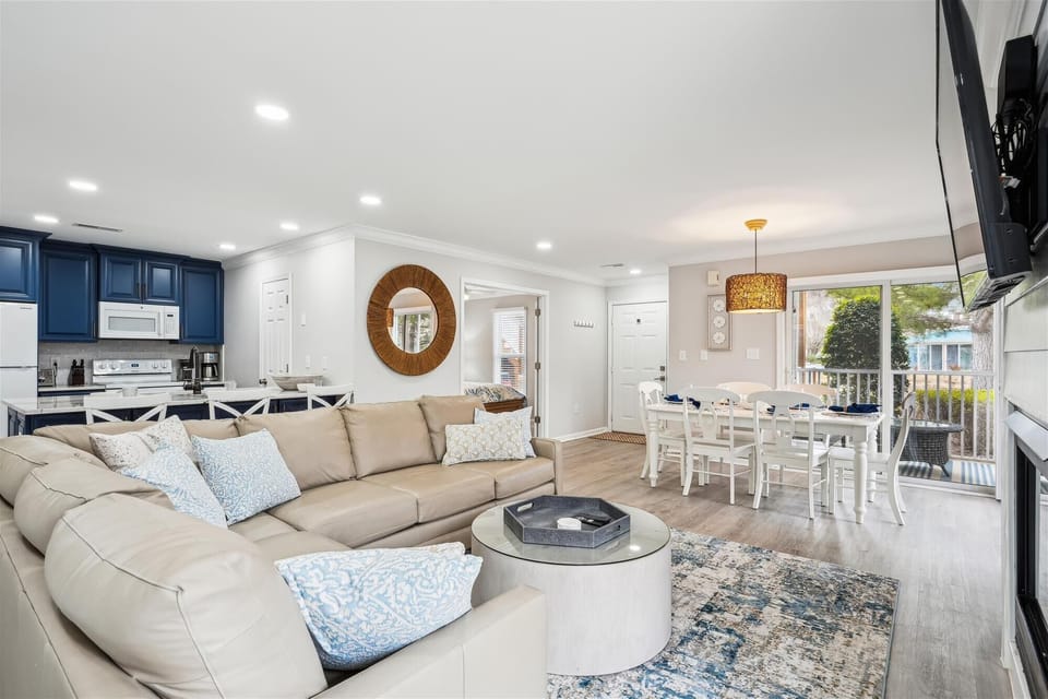 56152 Cypress Lake Circle - Great Room & Kitchen - This beautifully updated living area features a seamless flow between the kitchen, dining, and seating spaces. With crisp white cabinetry, modern navy accents, and stylish wide-plank flooring, the home offers a sophisticated coastal atmosphere perfect for entertaining.
