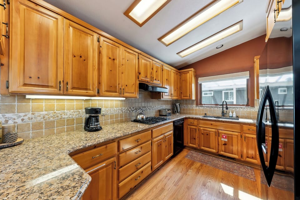 Your gourmet kitchen features warm wood cabinets, granite counters, and skylights that fill the space with natural light for cooking memorable meals.