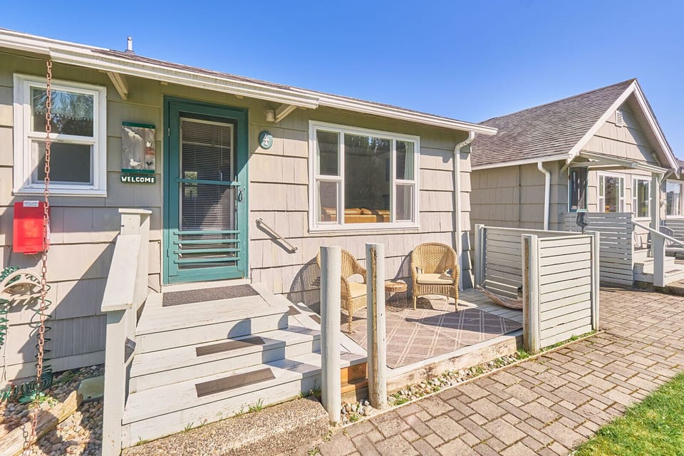 Back view of the cottage with access to a cozy patio—featuring outdoor seating, perfect for enjoying a quiet moment outdoors.
