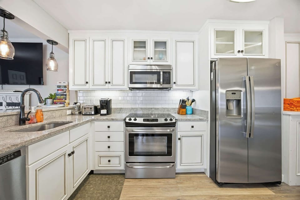Granite counters and subway tiles create a bright, gleaming kitchen perfect for slow mornings. Stainless appliances and warm wood floors provide a clean, modern space where you can brew coffee and prepare a quiet breakfast.