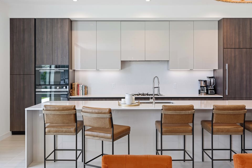 Modern kitchen island with leather bar stools and sleek wood cabinetry.