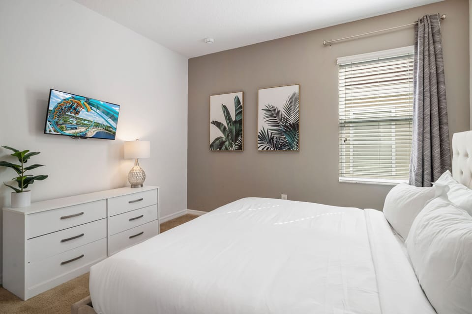 - Modern bedroom with plush bedding and tropical wall art  
- Smart TV and dresser for convenience during your stay  
- Natural light brightens this relaxing Orlando retreat