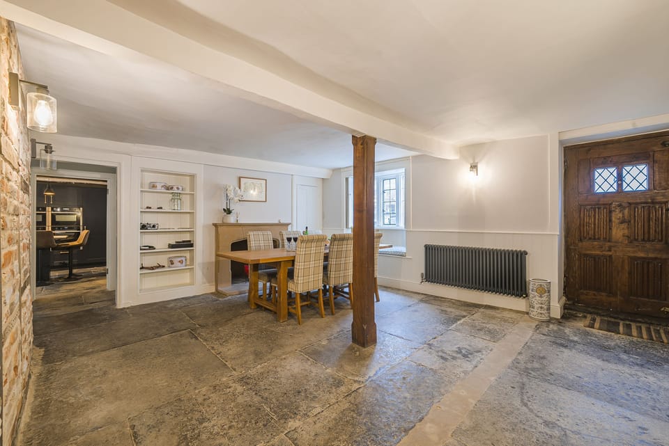 Beech House, Evershot: The dining room with flagstone flooring, window seat, beams and the original front door