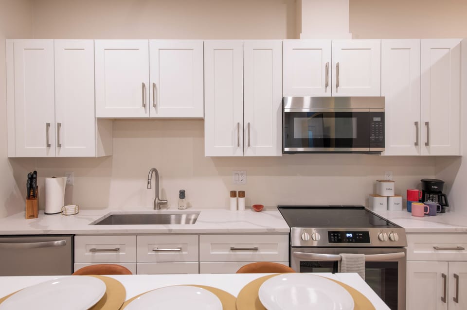 - Sleek white kitchen features stainless steel appliances, full stove, and overhead microwave
- Extra cabinet space and modern finishes keep everything clean and functional
- Bar seating at the counter makes casual dining and entertaining simple