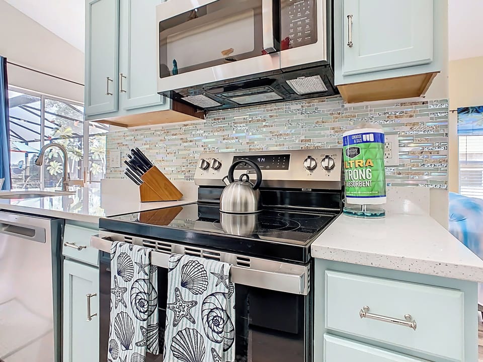 - Stainless steel stove and microwave surrounded by shimmering mosaic backsplash
- Handy knife set, kettle, and paper towels included for your cooking convenience
- Beachy shell patterned dish towels bring the ocean vibes right to the kitchen