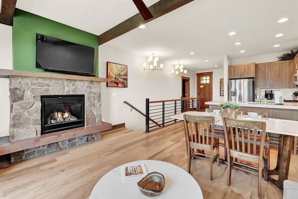 This spacious great room features a stone fireplace, dining area, and easy flow into the kitchen, perfect for relaxing and reconnecting.