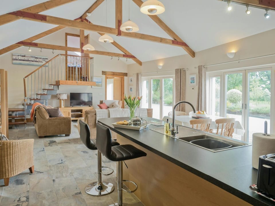 Open plan kitchen/living room: breakfast bar with sink and two bar stools