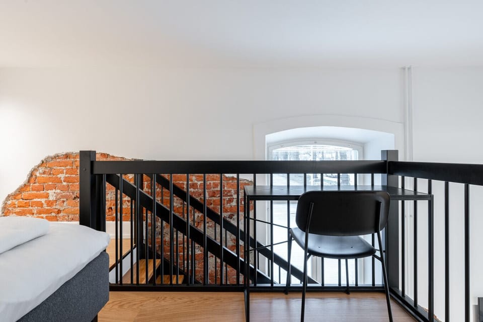 This dedicated workspace on the loft offers a quiet, elevated corner for catching up on emails or studying in peace. The ergonomic setup ensures you can work comfortably while enjoying a partial view of the apartment`s historic brick features.
