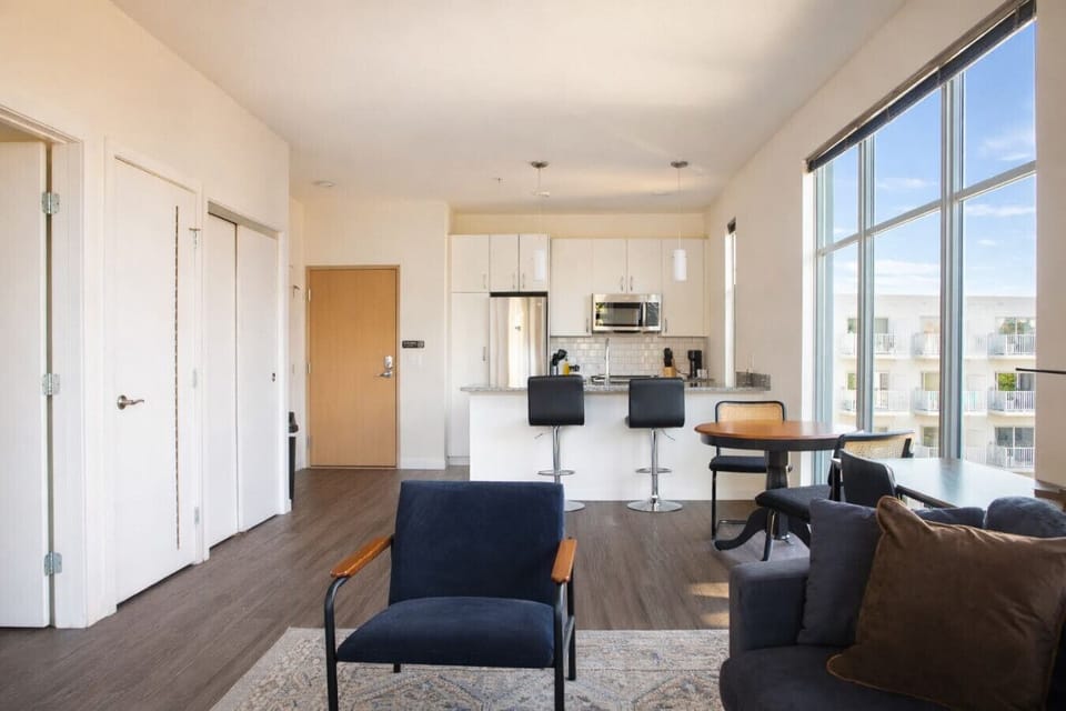 Unwind in the sun-drenched living area, complete with a dedicated workspace, dining table/workspace, and a private balcony for your morning coffee