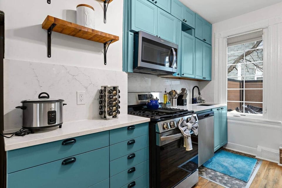 Full kitchen featuring turquoise cabinetry and a butcher block island for meal preparation
