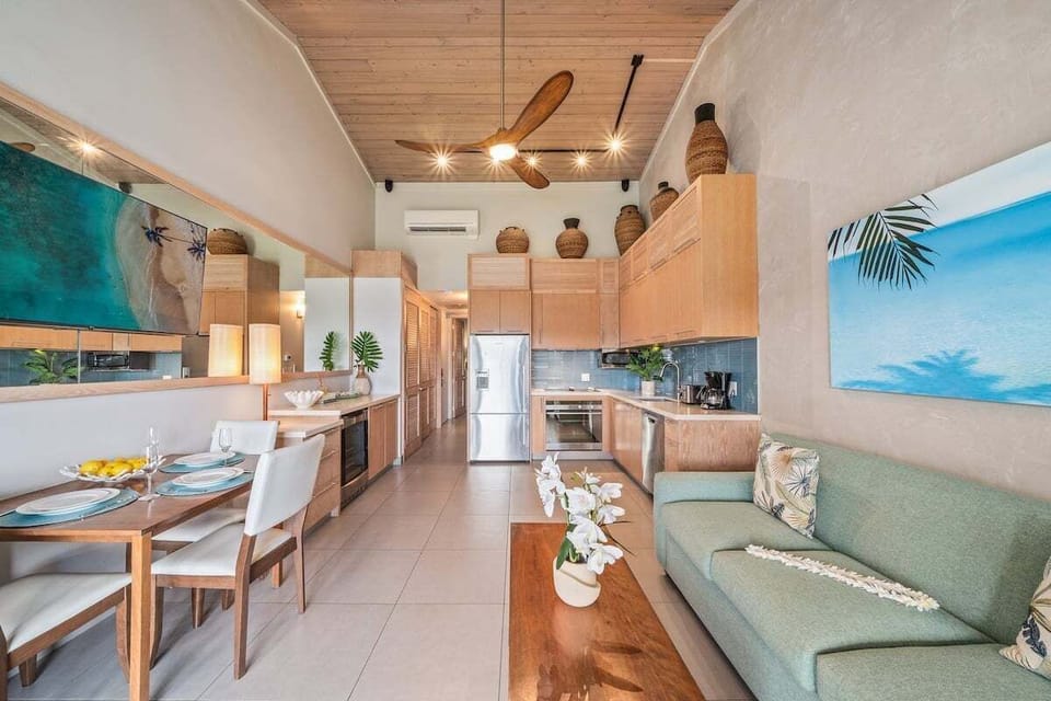 A bright, modern open-concept space featuring vaulted wood ceilings, a comfortable lounge area, and a sleek dining setup.