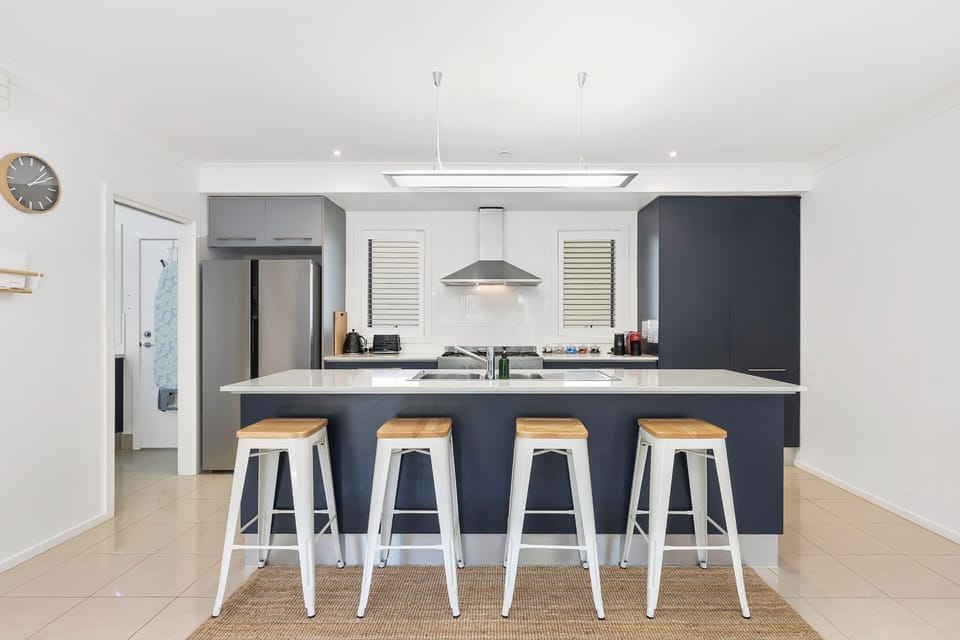 The kitchen features a spacious island bench with bar stools, the perfect spot for casual breakfasts