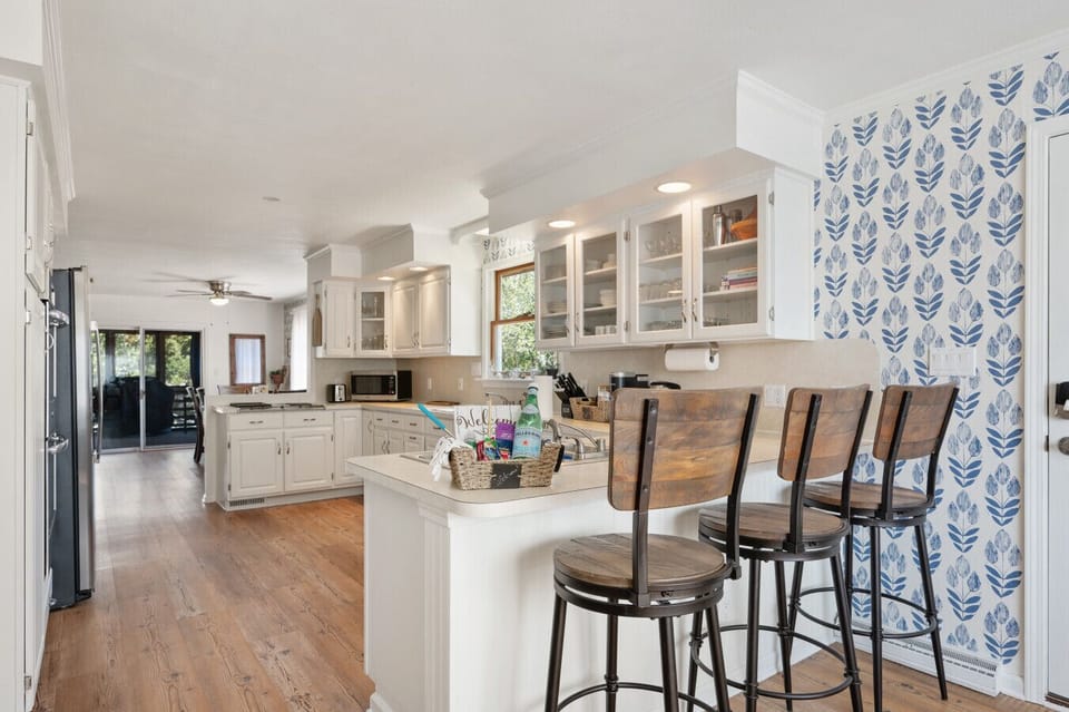 Bright kitchen w/ white cabinets, bar seating, & easy flow into dining and living spaces.