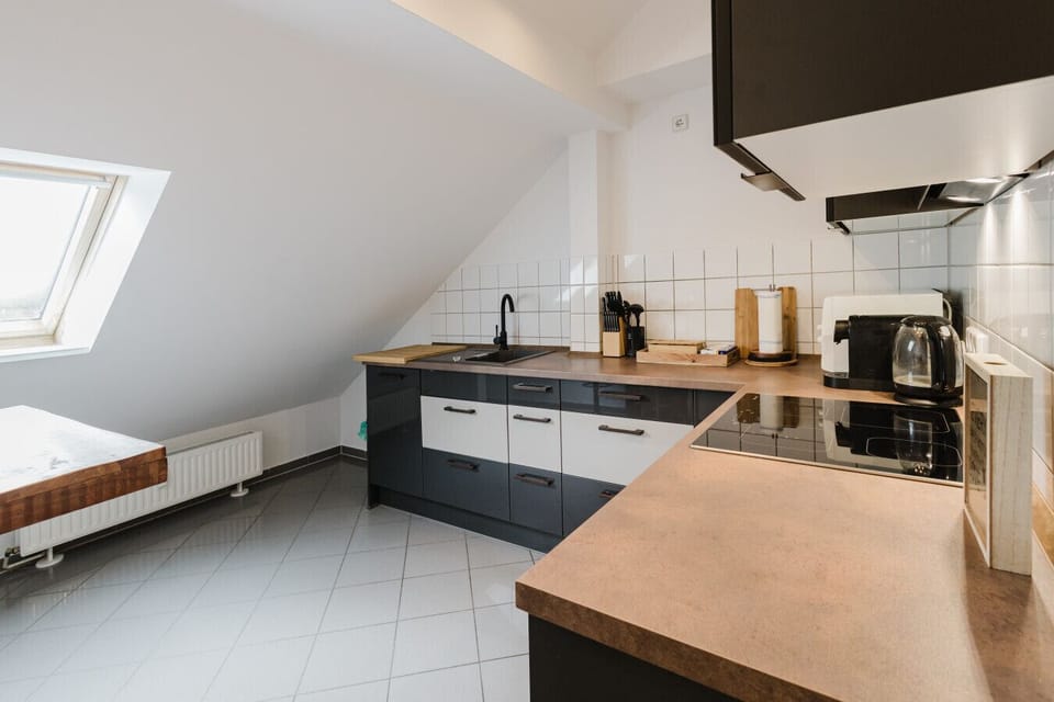 Fully equipped modern kitchen with sloped ceiling and coffee station.