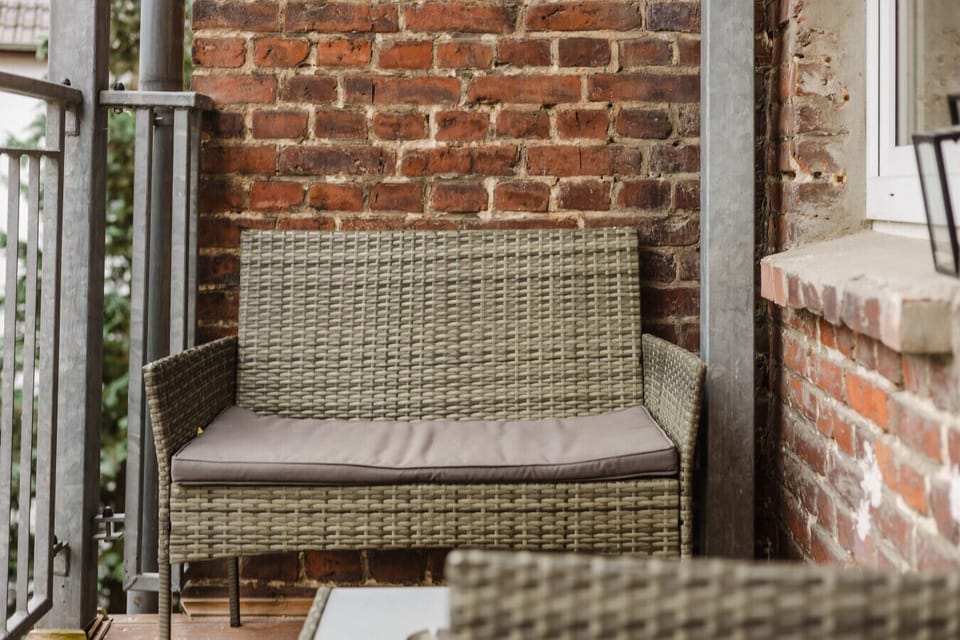 Rustic brick balcony with cozy rattan seating – ideal for fresh-air moments.