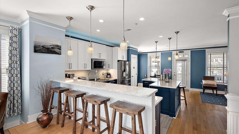 Four stool seats at kitchen counter besides two eating tables seating a total of 14