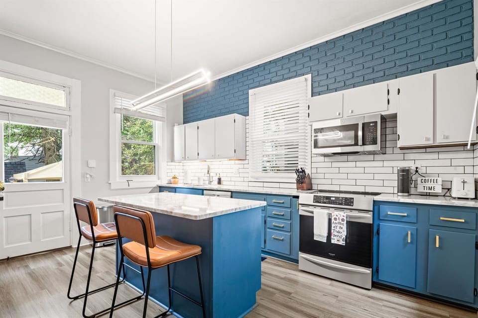 Bright, fully updated kitchen featuring custom blue cabinetry, quartz island with seating, stainless steel appliances, and modern finishes throughout—Perfect for cooking, gathering, and starting your day in German Village. Coffee and supplies provided.