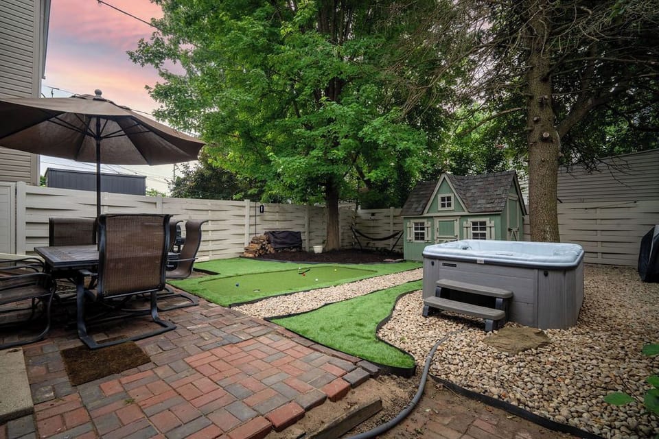 Private backyard retreat with covered dining, grill, outdoor TV, hot tub, and a kids’ playhouse. Turf games and shaded space make it perfect for relaxing and family fun, day or night.
