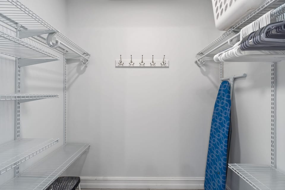 Large walk-in closet with ironing board, hooks and basket