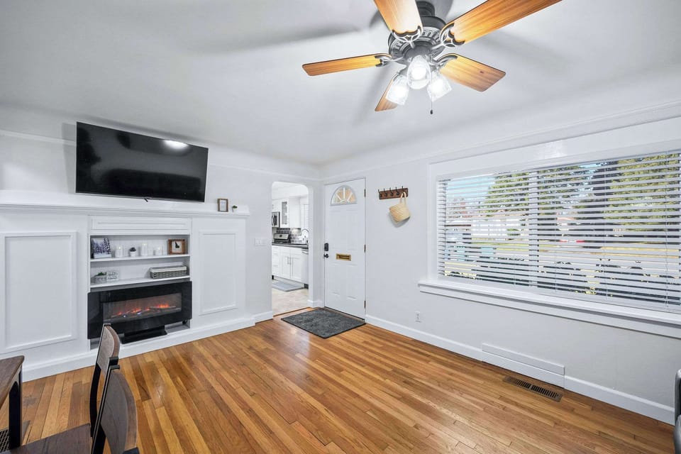 Relax in your bright living room with warm hardwood floors, cozy fireplace, and ceiling fan for perfect comfort year-round.