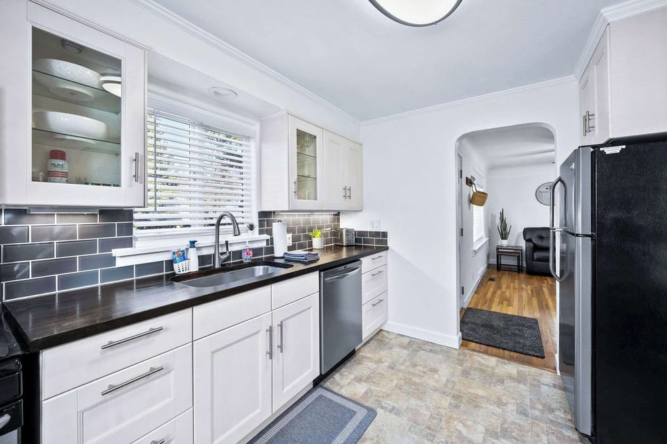 Your fully equipped kitchen features sleek white cabinets, dark countertops, and modern appliances for preparing delicious meals during your stay.