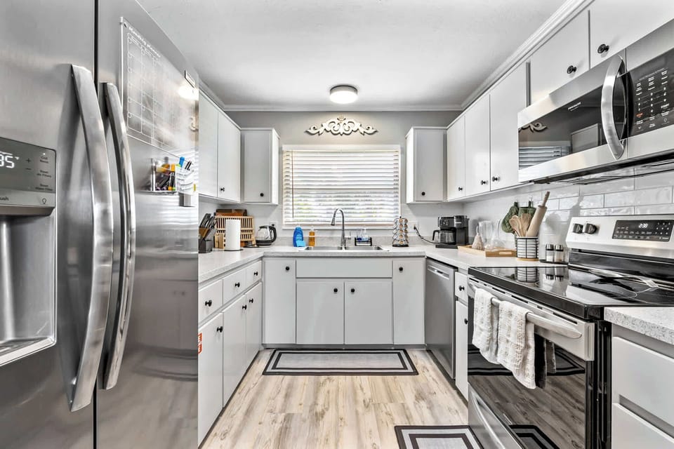 Modern kitchen with stainless steel appliances and ample white cabinetry.