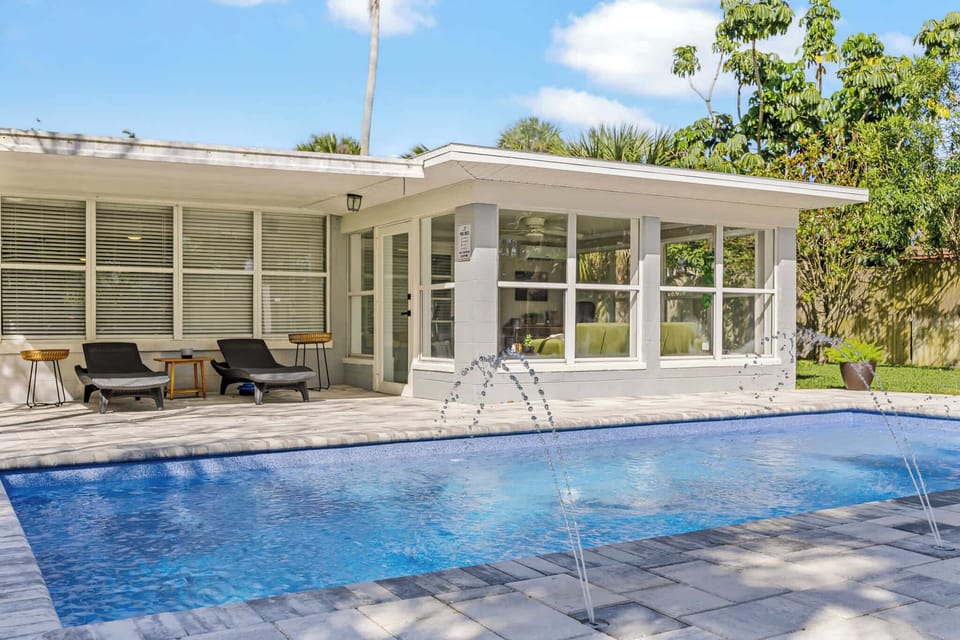 Modern patio area with lounge chairs overlooking a private pool with water fountains.