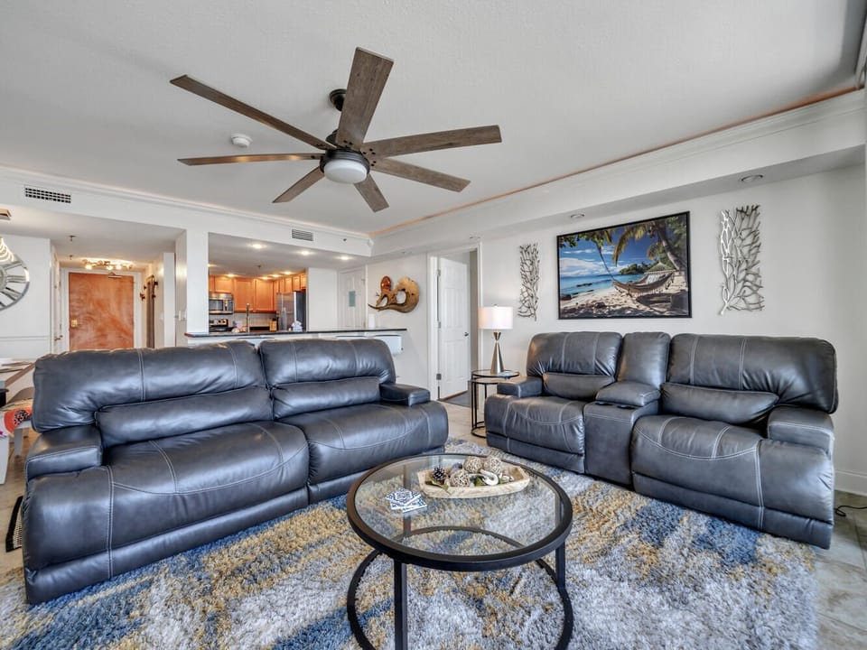 Unwind in your spacious living room with plush leather seating and ocean artwork creating the perfect coastal retreat atmosphere.