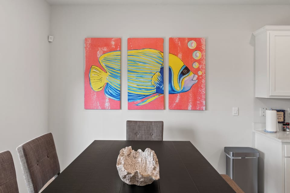 Gather around your stylish dining table beneath vibrant tropical fish artwork that brings ocean charm to every meal.