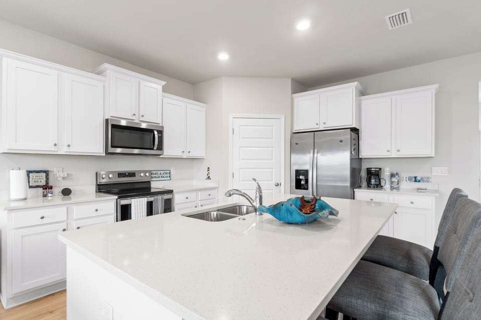 Your spacious kitchen awaits with pristine white cabinets, modern appliances, and a generous island perfect for cooking adventures.