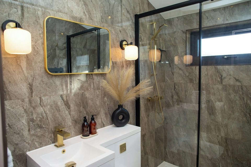 En suite shower room with large walk in shower, wash hand basin with mirror and lights over