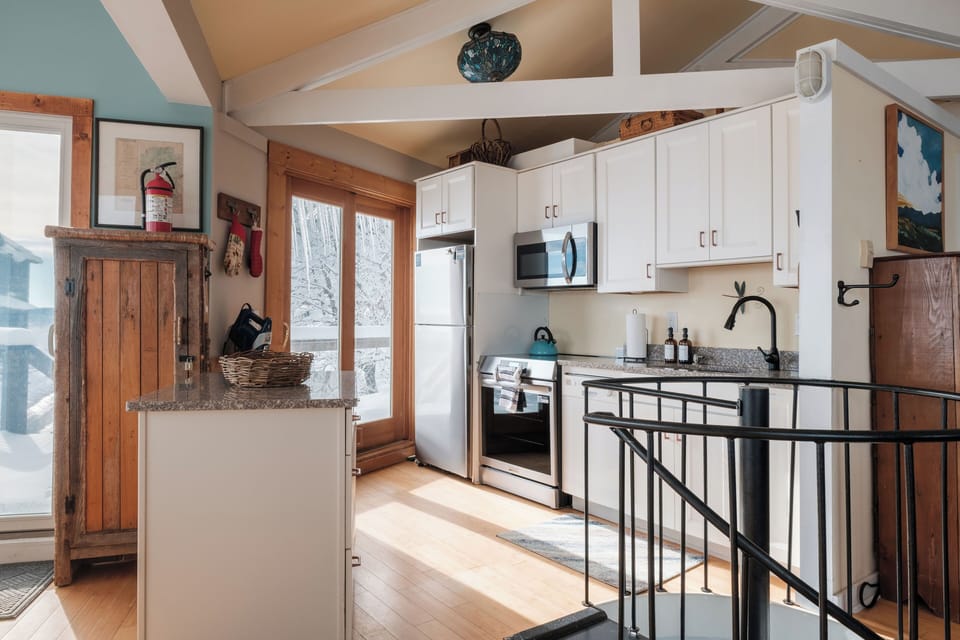 The open kitchen and dining area are bright, cozy, and perfectly equipped for shared meals after a day on the slopes. High ceilings and warm finishes make every gathering feel like home.
