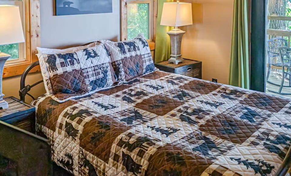 King bedroom with quilted bedding and panoramic window views of the Alarka forest and Smoky ridgelines