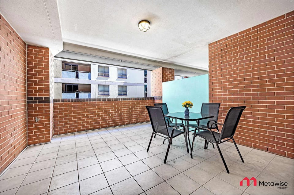 Private covered balcony with outdoor table and chairs, surrounded by brick walls.