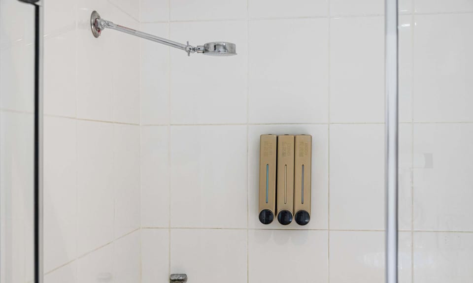 Shower area with wall-mounted amenities and tiled finishes.